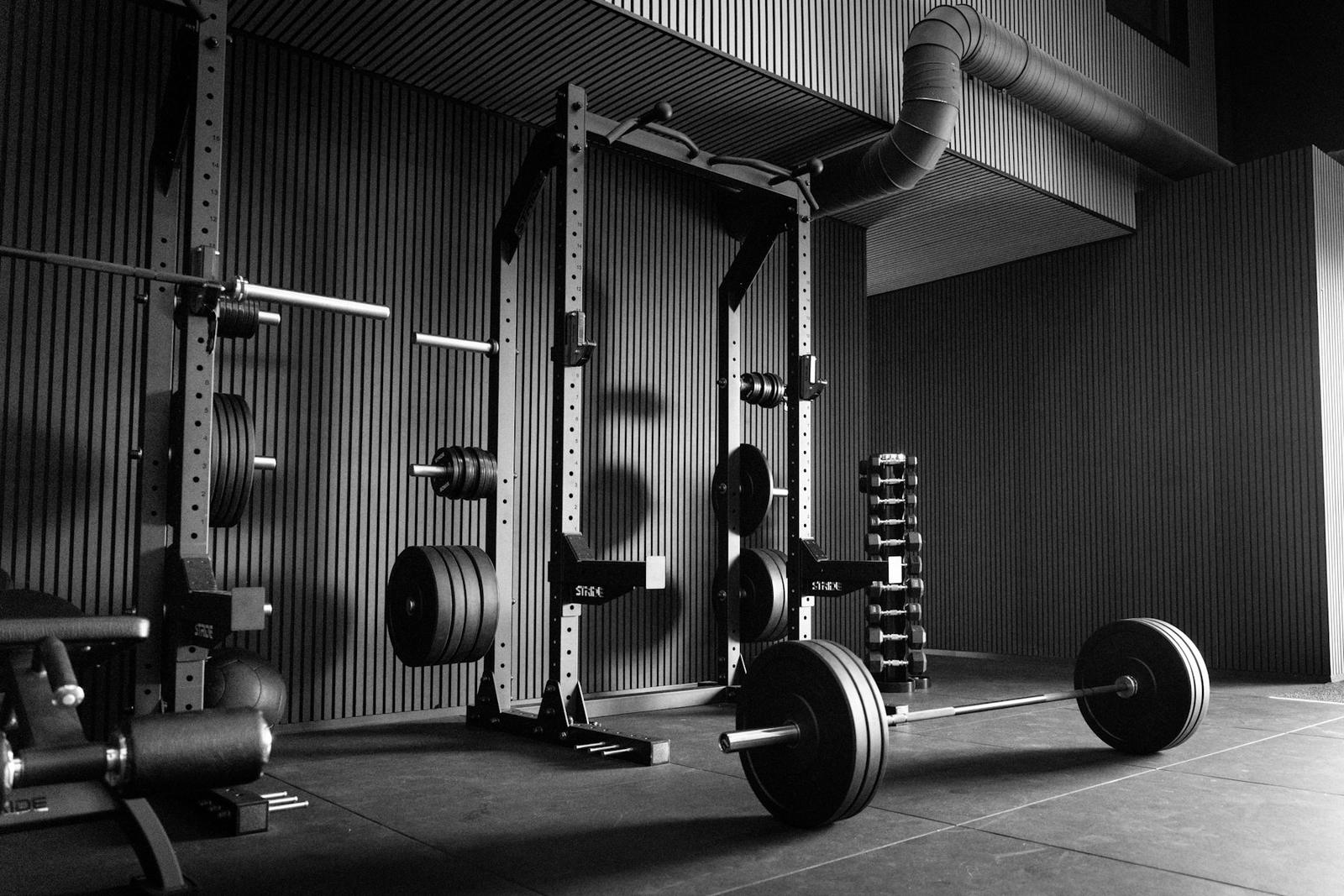 A power rack, barbell and plates in a dark gym
